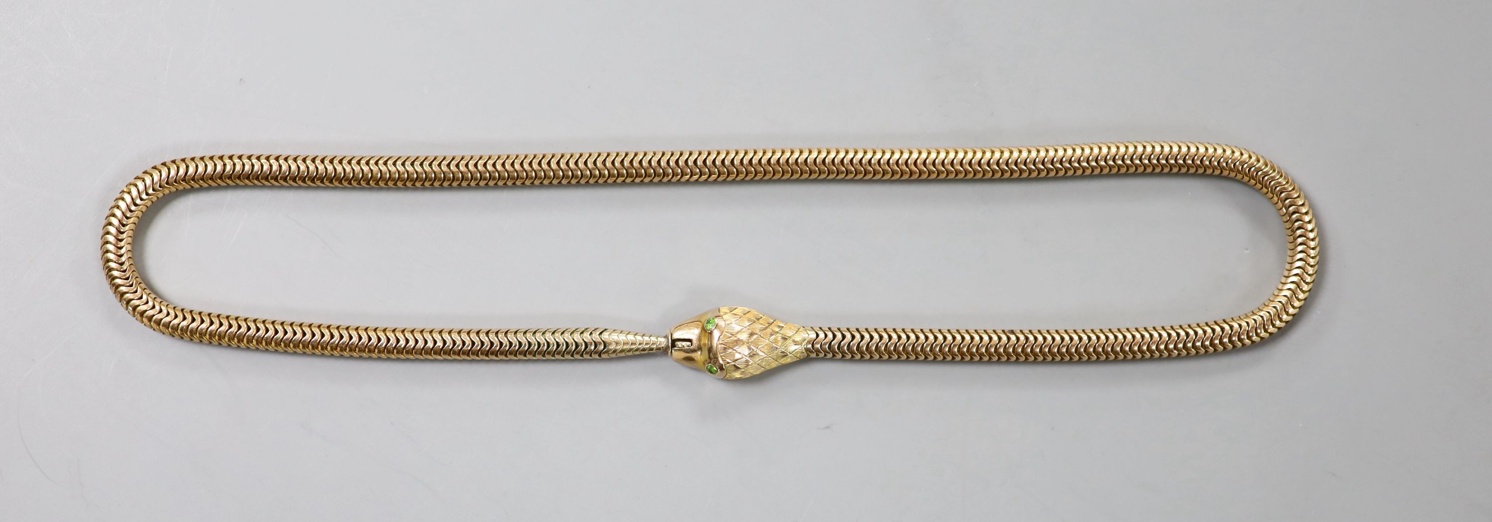 An Edwardian 9ct gold serpentine coil link serpent choker necklace, with green garnet set eyes, 36cm, gross 35 grams.